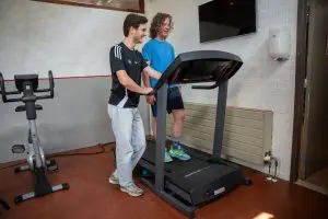 Kinderfysiotherapeut begeleidt kind op loopband tijdens sportfysiotherapie