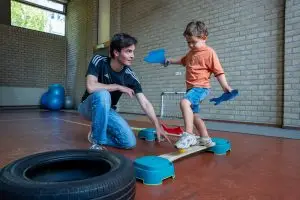 Kinderfysiotherapeut begeleidt peuter tijdens kinderfysiotherapie sessie
